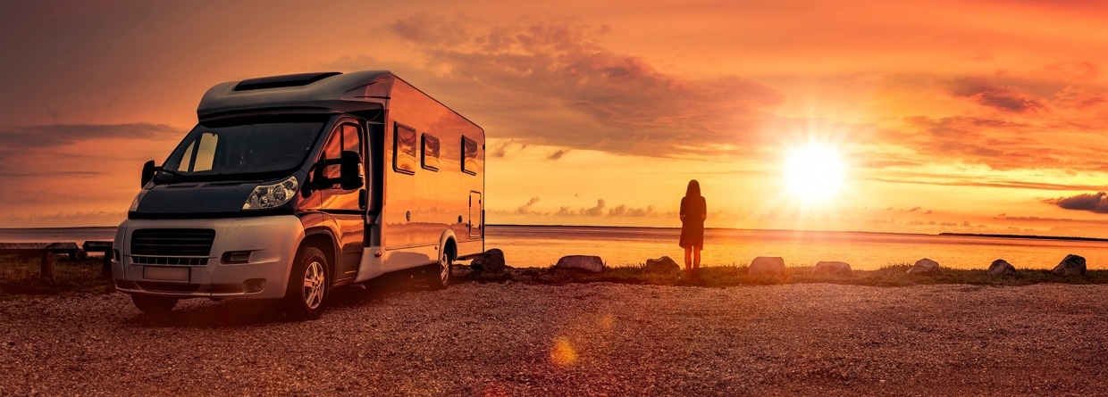 Vrouw bij zonsondergang met stacaravan op het strand