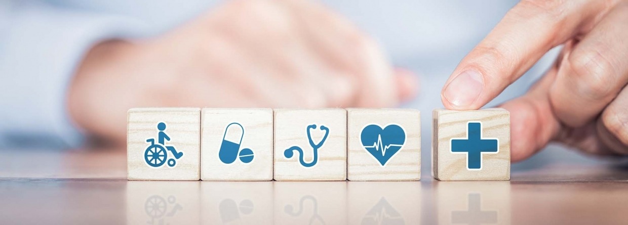 Zorgverzekering, houten blokjes met zorg icoontjes op de achtergrond een arts met stethoscoop om