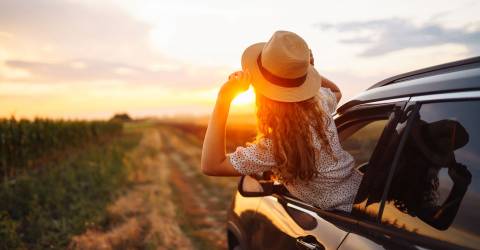 Ontspannen gelukkige vrouw op zomervakantie leunend uit autoraam