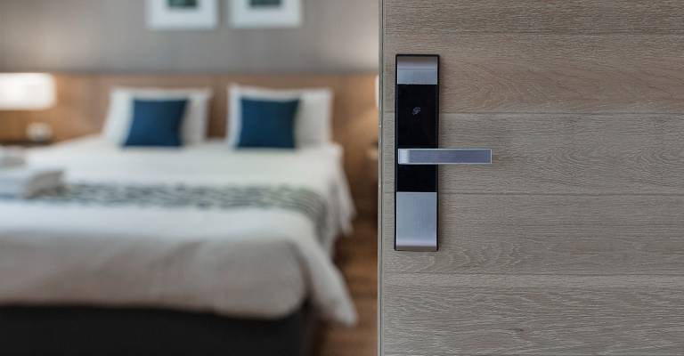 Open deur slaapkamer van vakantieverblijf met een bed op de achtergrond