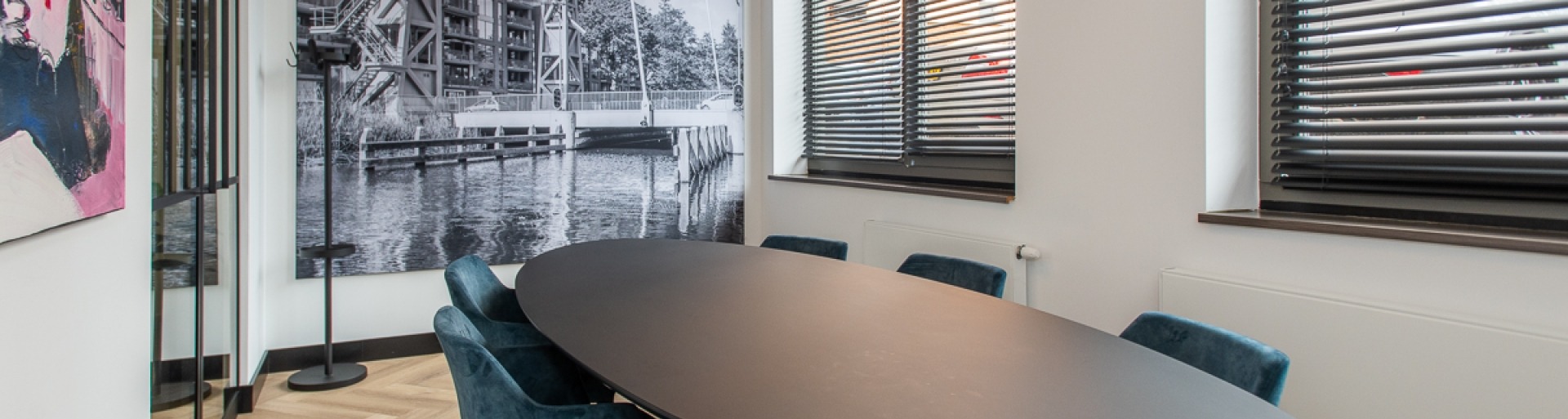 De spreekkamer bij T&W Tilburg met een grote zwarte tafel en blauwe stoelen